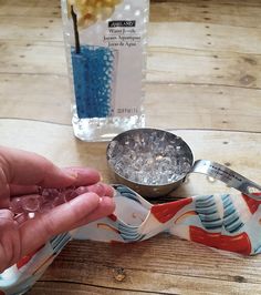 a person holding something in their hand next to a measuring cup and spoon on a table