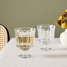 two glasses sitting on top of a table next to a vase with flowers in it