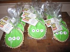 some green cookies with googly eyes are on a table and packaged in plastic bags