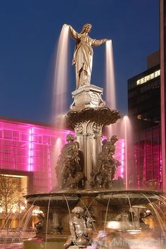 a fountain in front of a building with pink lights