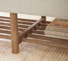 two books are stacked on top of each other near a bed frame with wooden slats