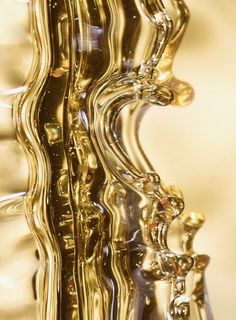 the reflection of an abstract gold sculpture is seen in this image, with its wavy lines and curves