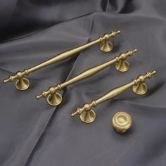 three brass handles and two knobs on a gray satin sheet with a wax seal