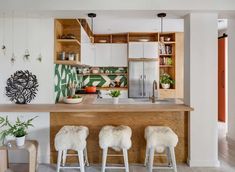 three stools sit at the bar in this modern kitchen with white walls and flooring