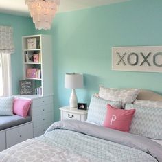 a bedroom with blue walls and gray bedding, pink pillows, and white furniture