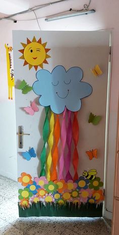 a door decorated with tissue paper and rainbows, sun and clouds on it's side