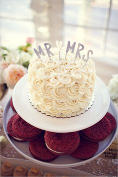 a cake with the word mr and mrs on it is sitting on a plate surrounded by cookies