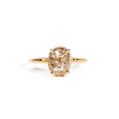 a yellow gold ring with an oval shaped diamond in the center, on a white background