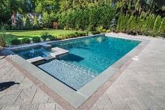 an empty swimming pool in the middle of a yard with stone pavers around it