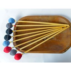 a wooden tray with knitting needles and balls of yarn