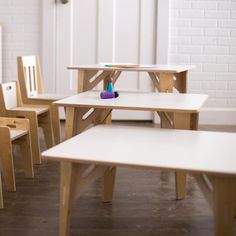 several children's wooden chairs and tables in a room with white brick wall behind them