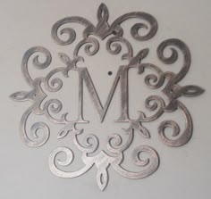 an ornate metal monogram with the letter m in it's center, on a white background