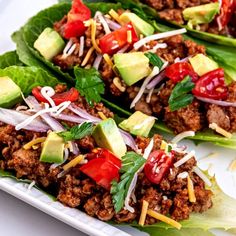 three lettuce cups filled with meat and veggies on a white plate