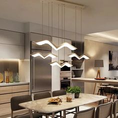 a modern kitchen and dining room are shown in this image, with the lights hanging from the ceiling