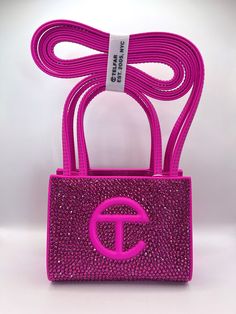 Introducing The Pink Friday Telfar. No, our latest offering is not sports related. And she's not a hat. But, she sure is stunning. This authentic azalea Telfar bag (we don't believe in fakes or bootlegs in this house) is a first of its kind and encrusted with thousands of the highest quality matching rhinestones (we don't cut corners in quality either) to ensure show stopping, attention grabbing sparkle (it's kinda our thing). Each bag is like its namesake, a true original. And for us, dare we even say the Pinkprint.  As many Telfar fans will know, it's not every day these bags are available and it could be a long time before this color is in stock again. This bag is a one-of-one and once she's gone, she's gone. Original dust bag included. Please be aware before purchasing: for maximum dur Pink Basket Gift Ideas, Telfar Bag, Telfar Bags, Telfar Bag Outfit, Football Purse, Pink Football, Trendy Purses, My Style Bags, Luxury Bags Collection