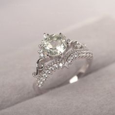 a white gold ring with an oval cut diamond surrounded by smaller round diamonds on the band