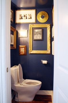 a white toilet sitting in a bathroom next to a framed wall with pictures on it