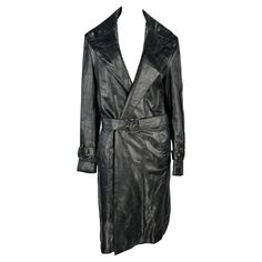 Designed by Donatella Versace for Versace's Fall/Winter 2005 men's collection, this coat debuted on the season's men's runway as part of look 5, modeled by Tyson Ballou. Constructed entirely of black leather, this sharp coat features a wide lapel, buckles at each wrist and is made complete with a matching belt. Approximate measurements: Size - removed Shoulder to hem: 42" Bust: 40 - 42" Waist: 38 - 40" Shoulder to cuff: 26" Underarm to cuff: 18" Versace Donatella, Tyson Ballou, Mens Runway, Donatella Versace, Belted Trench Coat, Raw Edge, Men's Collection, Versace, Trench Coat