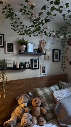 two teddy bears sitting on a bed in a room with many pictures and plants hanging from the ceiling