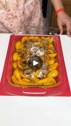 there is a red tray with food in it on the table and a woman standing next to it