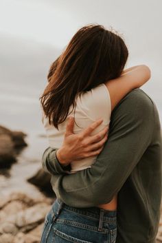 two people embracing each other by the water