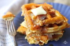 a blue plate topped with waffles covered in bacon and cheese next to a fork