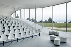 a large room filled with white chairs next to tall windows