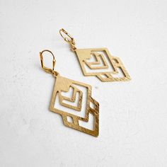 Add a modern touch to your style with this pair. Featuring geometric shapes, these earrings are chic and versatile. · Signature brushed gold plating on brass · Leverback clasp · 2.25" drop Modern Gold-plated Linear Earrings With Ear Wire, Modern Gold Plated Linear Earrings With Ear Wire, Modern Gold-tone Drop Linear Earrings, Modern Matte Gold Drop Earrings, Modern Matte Gold Metal Earrings, Modern Brass Earrings For Party, Modern Matte Gold Brass Hoop Earrings, Modern Brass Linear Earrings For Party, Elegant Geometric Gold Earrings