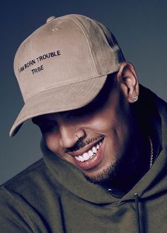 a man wearing a tan hat and smiling at the camera with his nose ring in front of him