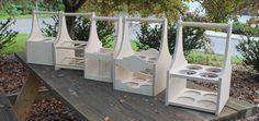 four white vases sitting on top of a wooden table in front of a tree