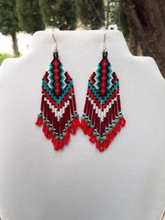 Beautiful Native American Style Beaded Rug Earrings in Black, White, Red and Turquoise. They are 4 inch long and 1 inch wide, with Twisted Red Glass Bugle Beads on them. If you like these but would like other Colors just email me.Thanks for looking. Adjustable Red Beaded Fringe Earrings, Red Southwestern Dangle Earrings, Southwestern Red Dangle Earrings, Southwestern Style Red Dangle Earrings, Traditional Red Beaded Fringe Jewelry, Southwestern Red Beaded Dangling Earrings, Southwestern Red Beaded Earrings With Dangling Beads, Southwestern Red Earrings With Colorful Beads, Red Bohemian Beaded Fringe Jewelry