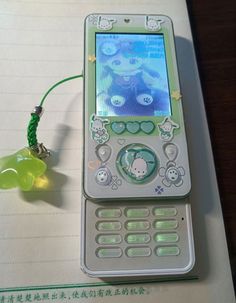 a cell phone sitting on top of a notepad next to a green string with beads