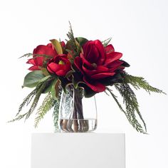 a vase filled with red flowers and greenery