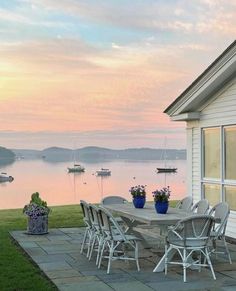 a table and chairs on a patio overlooking the water with boats in the lake behind it