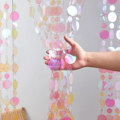 a person holding something in their hand near a wall with circles on it and chains hanging from the ceiling