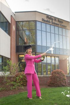 a woman in a pink suit and cap is holding a sparkler outside of a building