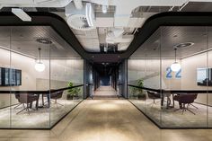 an office with glass partitions and tables in the center, along with potted plants