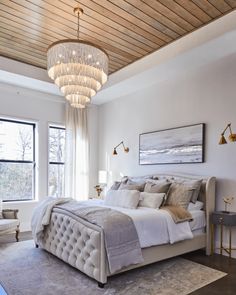 a bedroom with a large bed, chandelier and two lamps on the ceiling