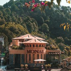 a large building sitting on the side of a lush green hillside next to a forest