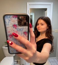 a woman taking a selfie in the bathroom with her cell phone up to her face