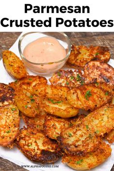 some fried potatoes on a white plate with dipping sauce in the middle and text overlay that reads parmesan crusted potatoes