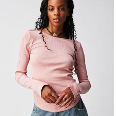 a woman wearing a pink sweater and jeans is standing with her hands in her pockets