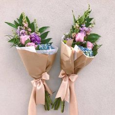 two bouquets of flowers wrapped in brown paper with pink and purple flowers on them