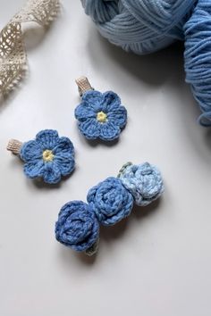 three crocheted flowers sitting on top of a table next to yarn and scissors