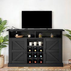 a flat screen tv sitting on top of a wooden entertainment center next to potted plants