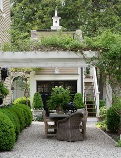 an outdoor dining area with potted plants on the table and stairs leading up to it