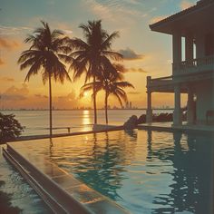 an empty swimming pool with palm trees in the foreground and sunset in the background