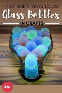 a vase filled with blue and green glass balls on top of a wooden table next to a