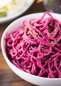 a white bowl filled with purple food on top of a wooden table