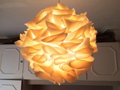 a large light fixture hanging from the ceiling in a kitchen with cabinets and cupboards